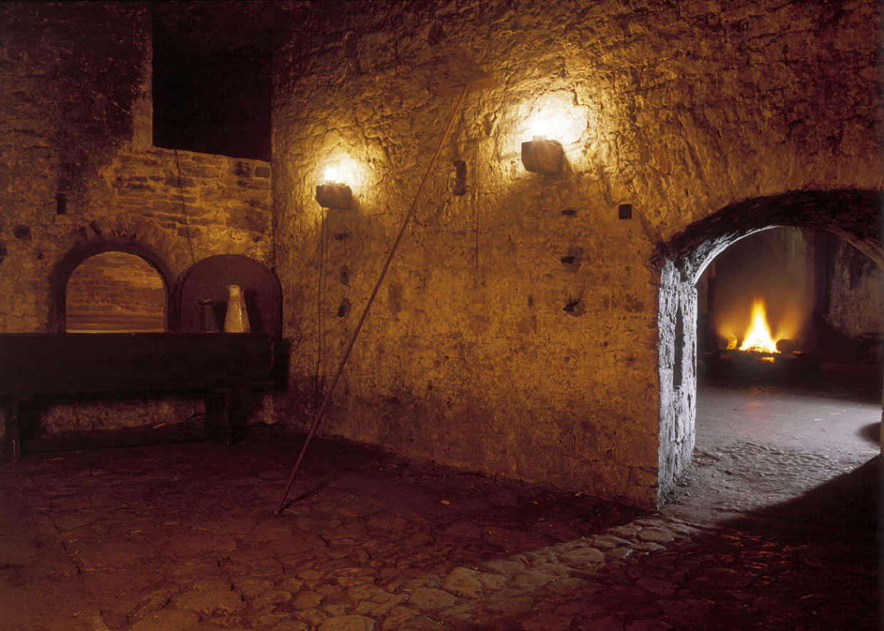 Mittelalterliche Burgkammer mit Steinmauern und flackernden Fackeln.